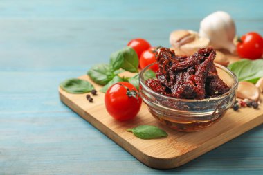 Lezzetli, kurutulmuş domatesler, taze sebzeler, fesleğen ve sarımsak mavi ahşap masada, yakın plan. Metin için boşluk