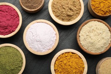 Siyah masa üzerinde farklı süper yiyecek tozları, düz uzanmış.