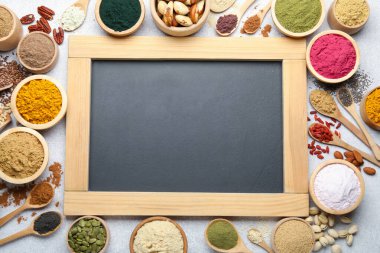 Farklı süper yiyecek tozları ve açık gri masa üzerinde karatahta, düz yatak. Metin için boşluk