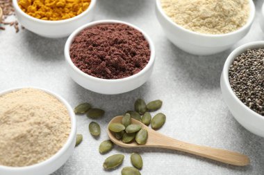 Açık gri masada farklı süper yiyecek tozları, yakın plan.