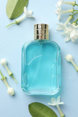 Parfüm ve yasemin çiçekleri açık mavi arka planda, düz yerde