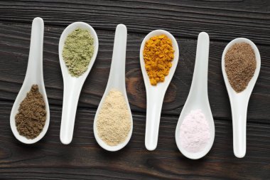 Tahta masadaki kaşıklarda farklı süper yiyecek tozları.