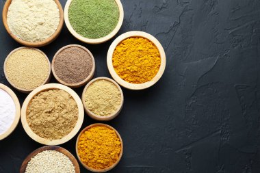 Koyu dokulu masada, düz yerde, kaselerde farklı süper yiyecek tozları var. Metin için boşluk