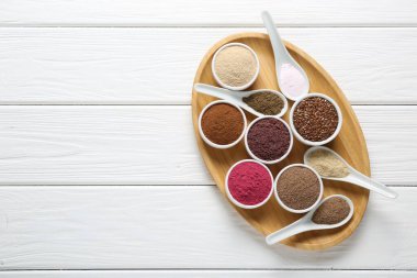 Kâselerdeki farklı süper yiyecekler ve beyaz ahşap masada kaşıklar, üst manzara. Metin için boşluk