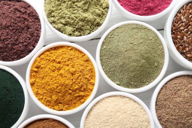 Beyaz ahşap masadaki kaselerdeki farklı süper yiyecek tozları.