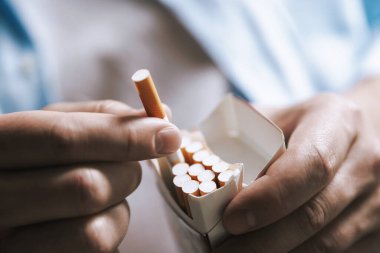 Sigarayı paketten çıkaran adam, yakın plan. Sigara içmek.