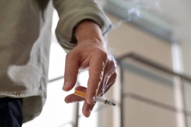 Arka planda sigara içen adam, yakın plan.