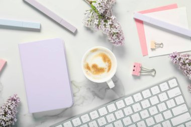 Kırtasiye malzemesi, kahve ve çiçeklerle bembeyaz mermer masa üzerinde düz bir kompozisyon.