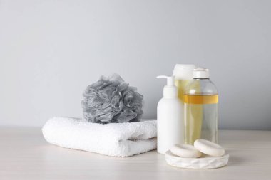 Açık ahşap masada gri arka planda farklı banyo aksesuarları, yakın plan.