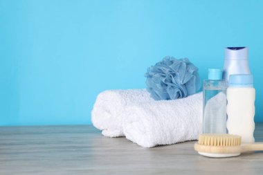 Açık mavi arka planda, ahşap masada farklı banyo aksesuarları, yakın plan. Metin için boşluk