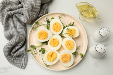 Haşlanmış yumurta, mikro yeşillik ve beyaz mermer masa üzerinde yağ, düz uzanmış