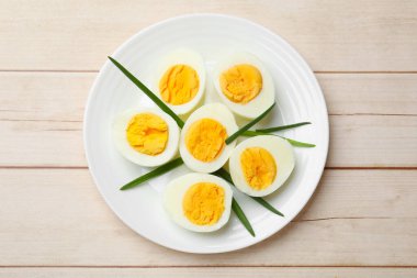 Haşlanmış yumurta ve yeşil soğan ahşap masada, üst manzara.