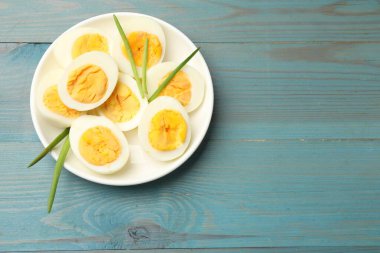 Mavi ahşap masada yeşil soğanlı haşlanmış yumurtalar, üst manzara. Metin için boşluk