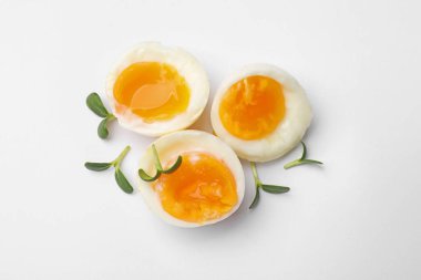 Beyaz arka planda mikro yeşillikli yumuşak haşlanmış yumurtalar, üst manzara.