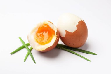 Beyaz arka planda yeşil soğanlı yumuşak haşlanmış yumurta.