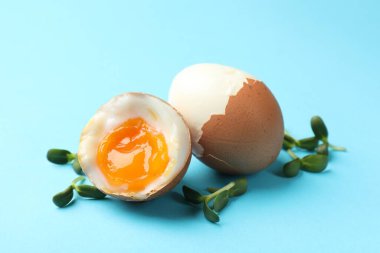 Hafif kaynamış yumurtalar ve açık mavi arka planda mikro yeşiller. Yakın plan.