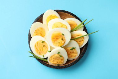 Açık mavi arka planda yeşil soğanlı haşlanmış yumurtalar.