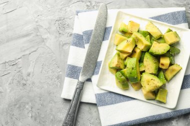 Gri desenli masa üzerinde soslu ve bıçaklı leziz avokadolar, üst manzara. Metin için boşluk