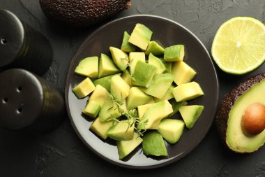 Lezzetli avokadolar, kekik ve limon siyah masada, düz yerde.