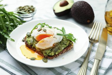 Avokadolu lezzetli sandviç, haşlanmış yumurta, roka ve balkabağı masada servis ediliyor, yakın plan.