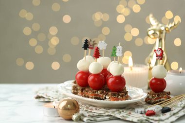 Lezzetli kanepeler ve beyaz mermer masanın üzerinde arka planda bulanık ışıklar ve yazı için yer olan Noel süslemeleri. Bokeh etkisi