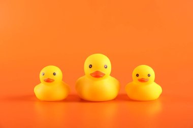 Turuncu arka planda üç sevimli lastik ördek.