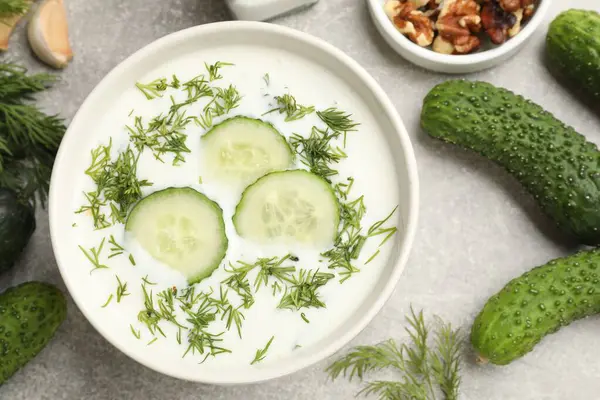 Lezzetli salatalık çorbası kasede dereotu ve gri desenli masada fındık.