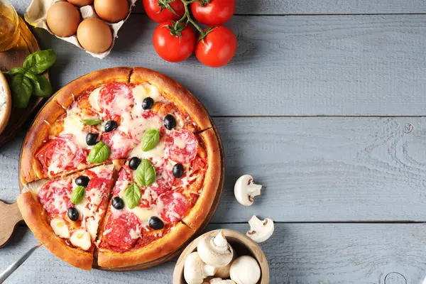Lezzetli pizza ve malzemeler gri ahşap masada, düz yerde. Metin için boşluk