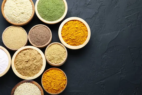 Koyu dokulu masada, düz yerde, kaselerde farklı süper yiyecek tozları var. Metin için boşluk