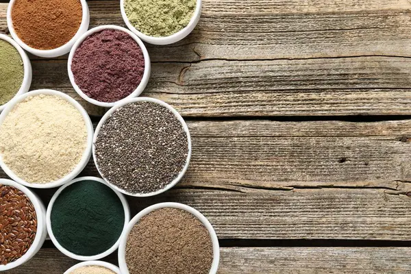 Tahta masadaki kaselerdeki farklı süper yiyecekler, düz yatış. Metin için boşluk