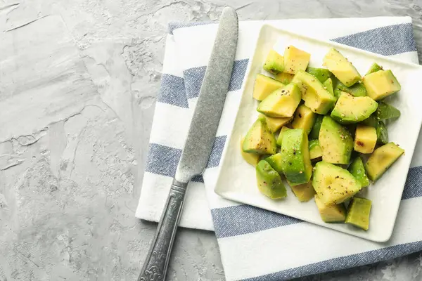 Gri desenli masa üzerinde soslu ve bıçaklı leziz avokadolar, üst manzara. Metin için boşluk