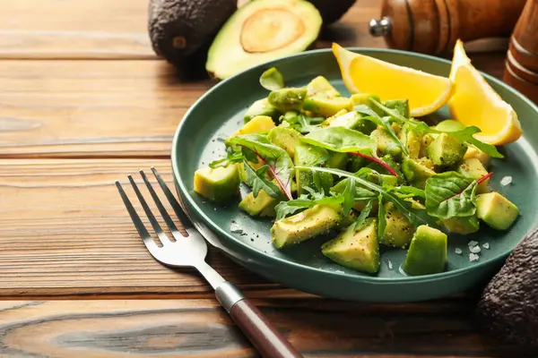 Lezzetli avokado roka, limon ve ahşap masaya sos, yakın plan.