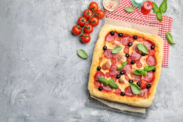 Lezzetli ev yapımı pizza ve malzemeler gri masada, düz yerde. Metin için boşluk