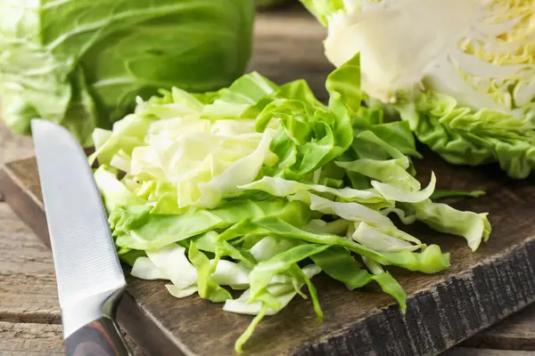 Taze kesilmiş lahanalar ve bıçak ahşap masada, yakın plan.