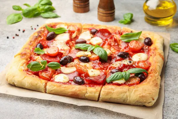Gri arka planda ev yapımı lezzetli pizza ve baharatlar, yakın plan.