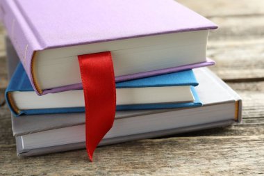 Kırmızı kurdele yer imi ve ahşap masa üzerinde renkli kitap, yakın plan.