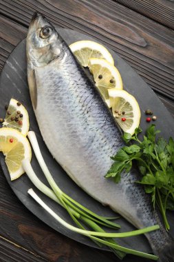 Ahşap masada tuzlanmış ringa balığı ve baharat, üst manzara.