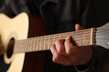 Siyah arkaplanda gitar çalan adam, yakın plan