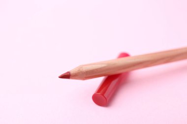 Açık pembe arka planda güzel bir dudak kalemi, yakın plan. Metin için boşluk