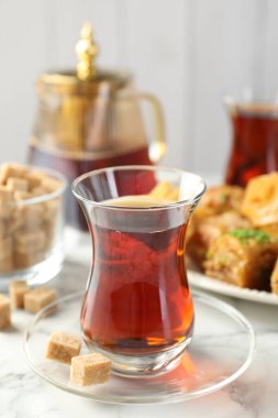 Lezzetli Türk çayı, beyaz mermer masada şekerlerle servis edilir, yakın plan.