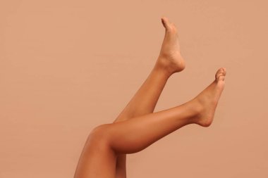 Epilasyon. Bej arka planda yumuşak tenli bacaklarını gösteren kadın, yakın plan.