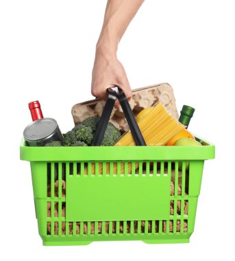 Beyaz arka planda farklı ürünleri olan alışveriş sepeti tutan adam, yakın plan.