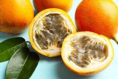 Olgun sarı tutku meyveleri ve açık mavi arka planda yapraklar, yakın plan.