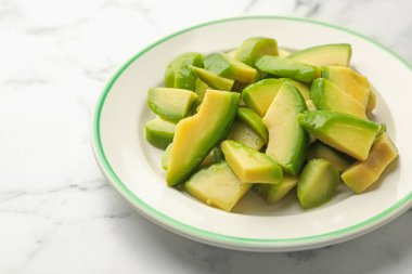 Beyaz mermer masada olgun yeşil avokadoyu kes, yakın plan.