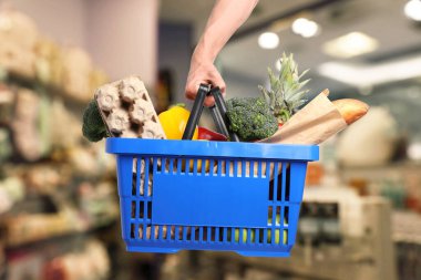 Süpermarkette elinde farklı gıda ürünleri olan bir adam var.