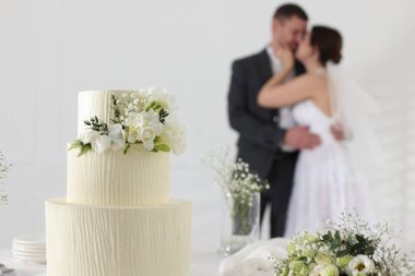 Mutlu evli çift içeride, düğün pastasına ve masadaki bukete odaklan.