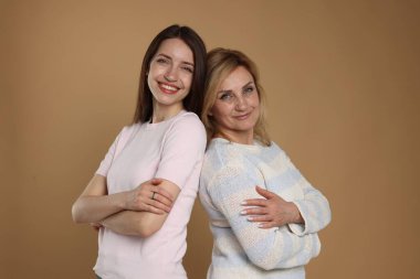 Neşeli anne ve kızı arka arkaya bej arka planda