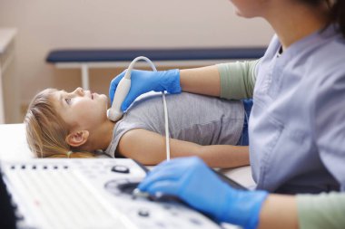 Sonograf, klinikte küçük kızın tiroid bezini ultrason muayenesi yapıyor.