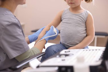 Sonograf, klinikte küçük bir kızın kolunun ultrason muayenesi yapıyor.