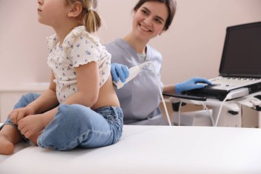 Küçük kızın böbrek ultrasonu muayenesini klinikte yapan sonograf.